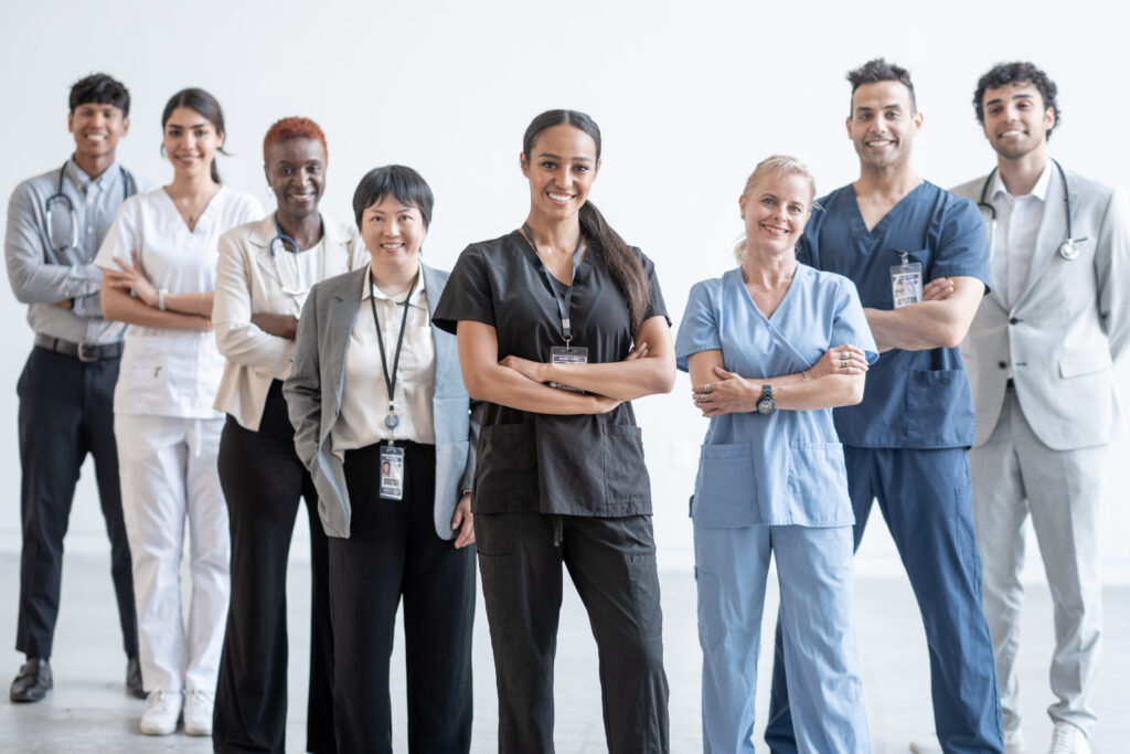 Diverse team of smiling doctors, nurses, and medical staff standing together in a bright, welcoming healthcare environment, representing inclusive healthcare careers and workplace culture.