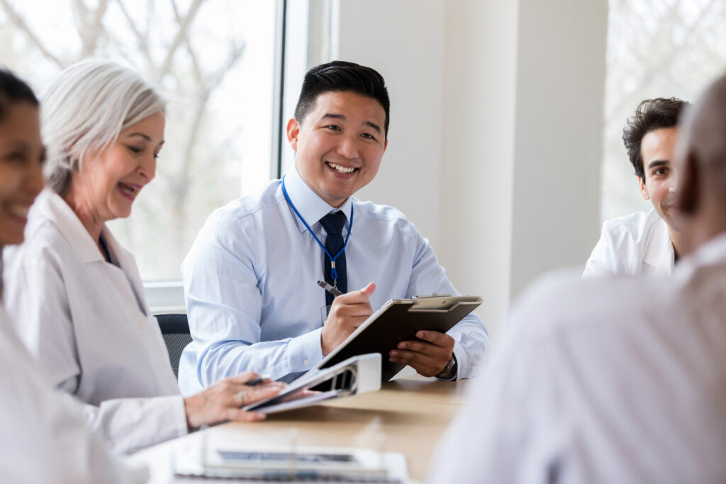 Diverse team of healthcare and business professionals collaborating in a bright room, representing Guidehealth's employer-focused approach to affordable workforce healthcare solutions.