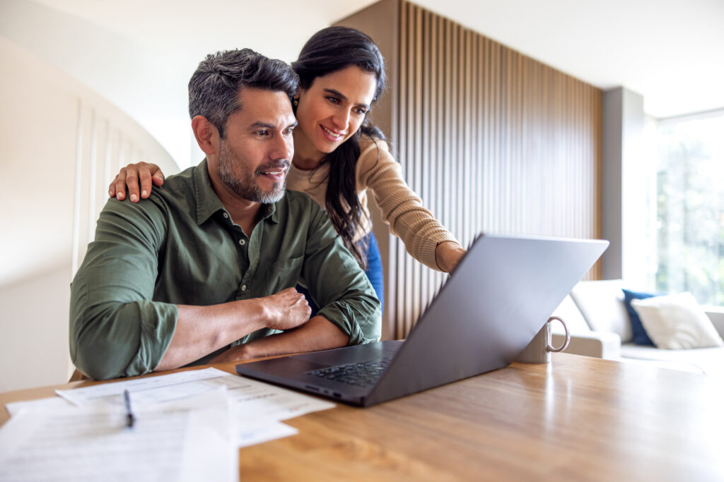 Couple reviewing healthcare benefits information together on a laptop at home, representing Guidehealth's accessible benefits enablement solutions for members and families.