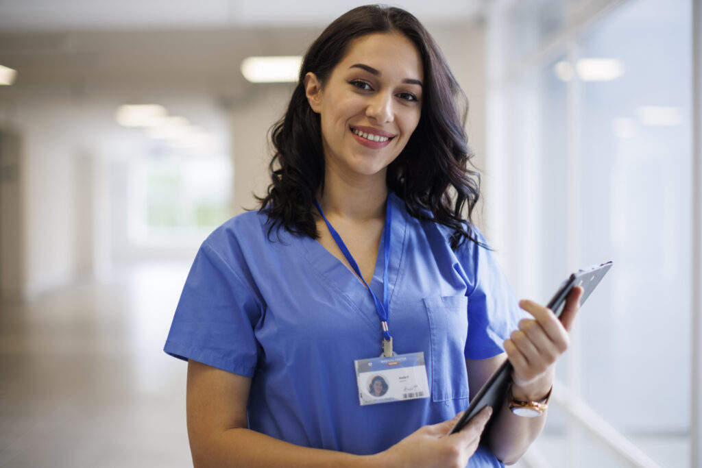 Smiling Guidehealth care manager holding a tablet in a hospital corridor, representing personalized care management and Human Healthguide support for patients.