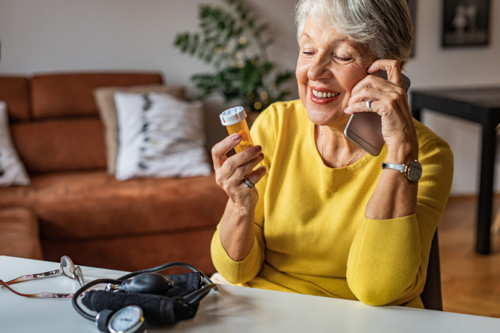 Senior patient at home reviewing medication and consulting by phone, representing Guidehealth's support for patients without primary care access through accessible whole-person healthcare.