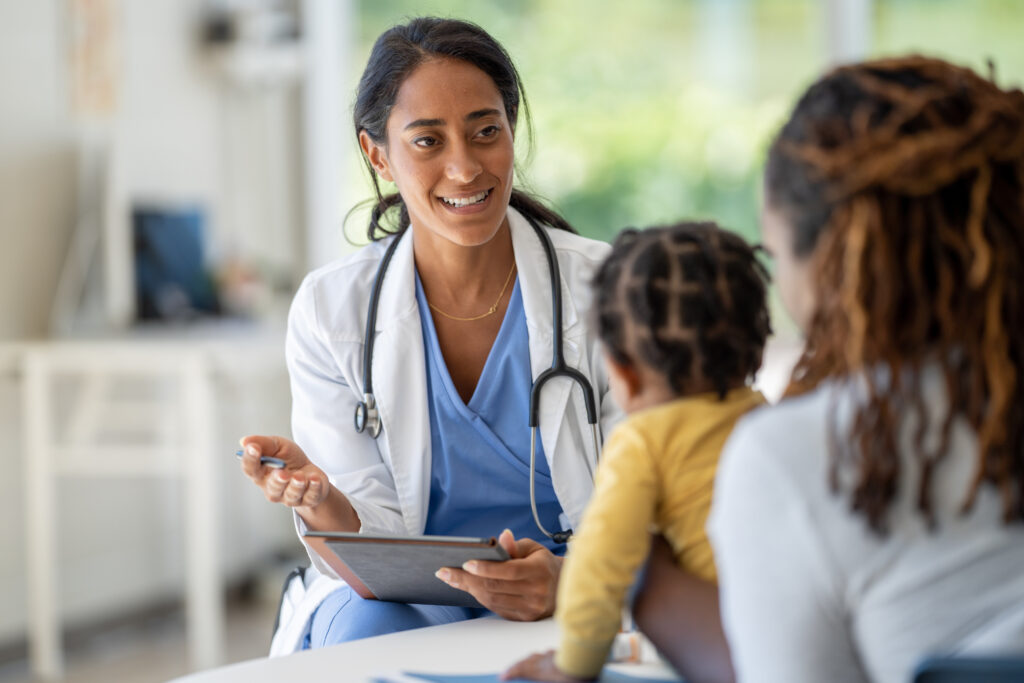 Healthcare provider consulting with a parent and child during a clinic appointment, representing accessible and affordable whole-person healthcare for families.